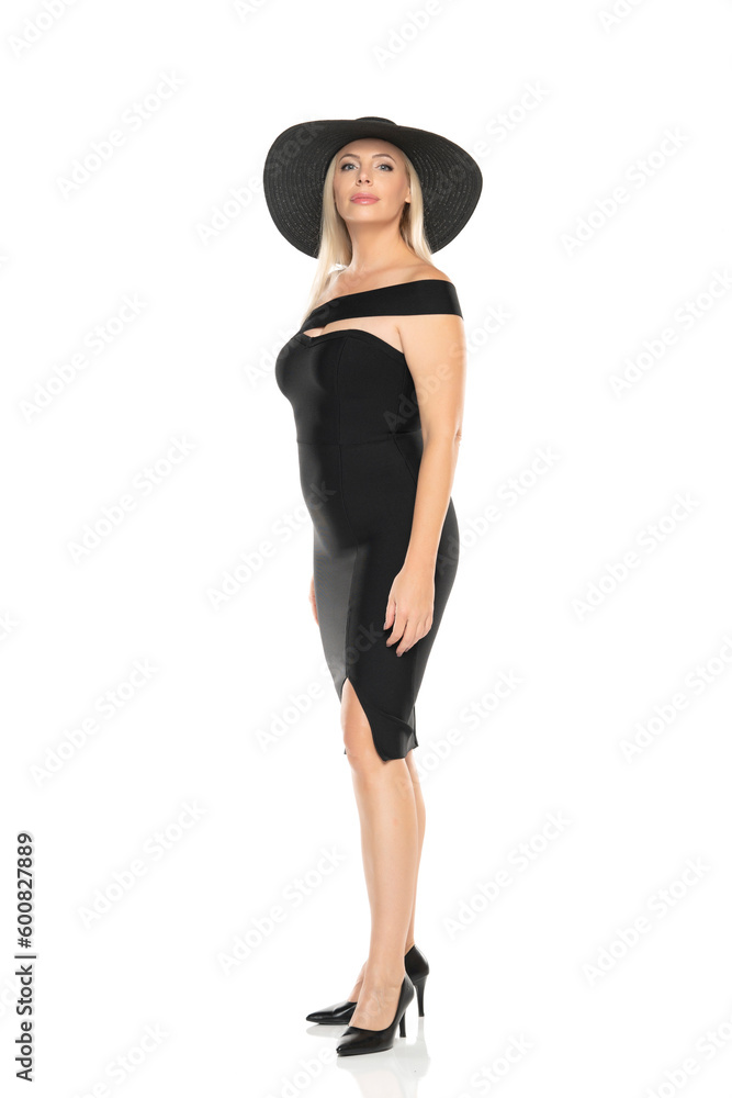 Middle aged senior woman in black tight dress and hat posing on a white background Middle aged senior woman in black tight dress and hat posing on a white background