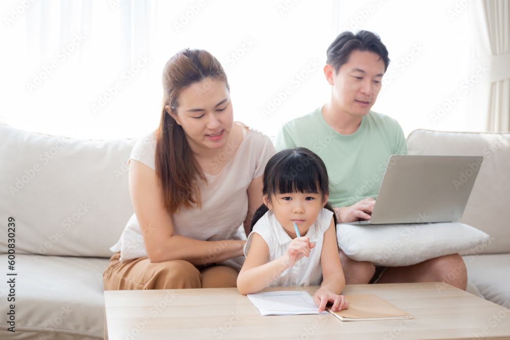 Happy family with mother teaching homework with daughter and father working with laptop on sofa in living room at home, mom explaining schoolwork with kid together, lifestyles and education. Happy family with mother teaching homework with daughter and father working with laptop on sofa in living room at home, mom explaining schoolwork with kid together, lifestyles and education.