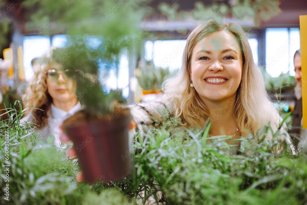 Fototapeta premium Asparagus in pot is held in hand of unfocused attractive blonde. Unpretentious plants for winter garden. Hobby. 