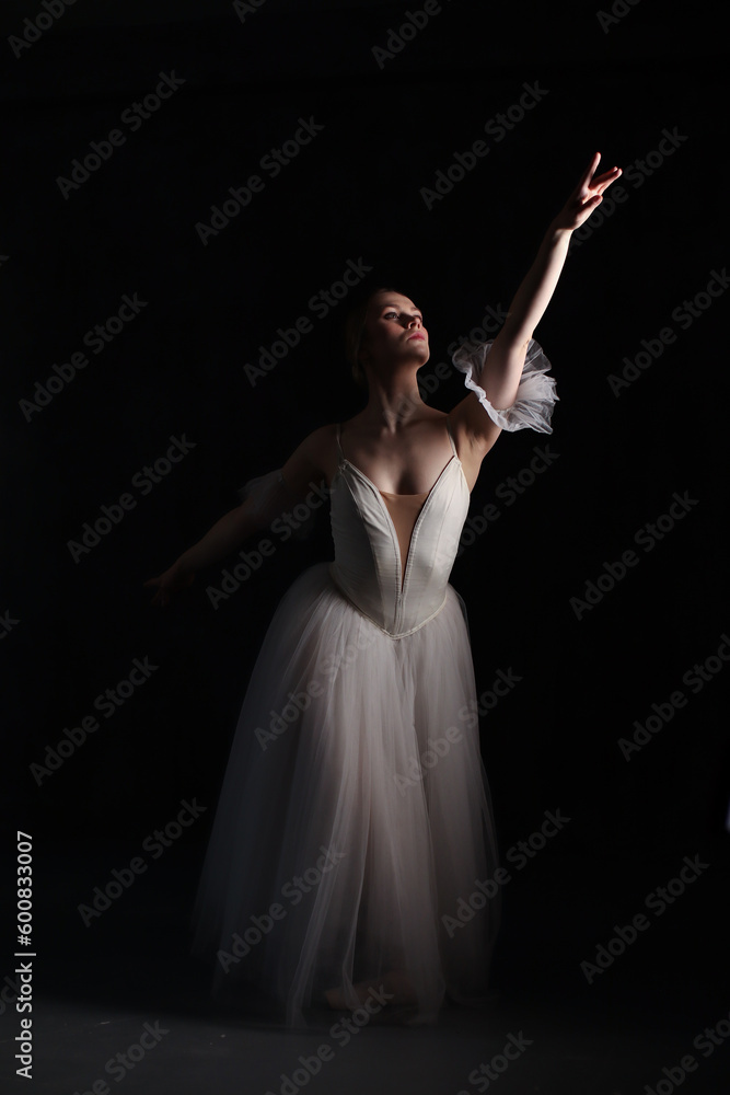 Professional ballerina dancing ballet.Ballerina in a white dress and pointe shoes. Dark background. Beautiful female body. Professional ballerina dancing ballet.Ballerina in a white dress and pointe shoes. Dark background. Beautiful female body.