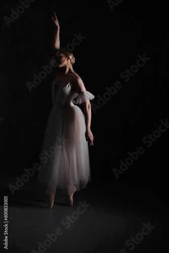 Professional ballerina dancing ballet.Ballerina in a white dress and pointe shoes. Dark background. Beautiful female body.