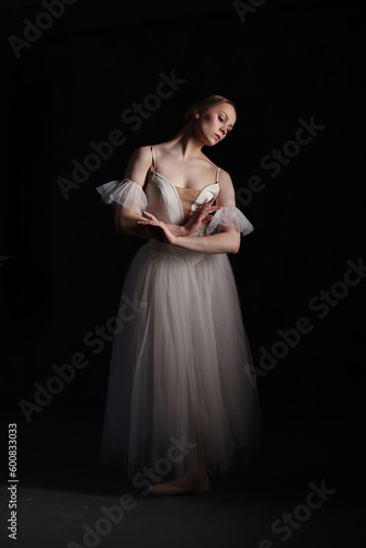 Professional ballerina dancing ballet.Ballerina in a white dress and pointe shoes. Dark background. Beautiful female body.