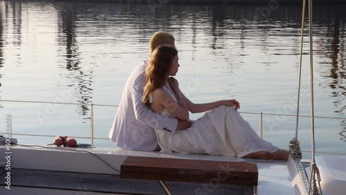 Couple in love young girl and guy spends time on yacht in sea. Summer, sea, sunrise, warm golden rays of sun. 4K Resolution