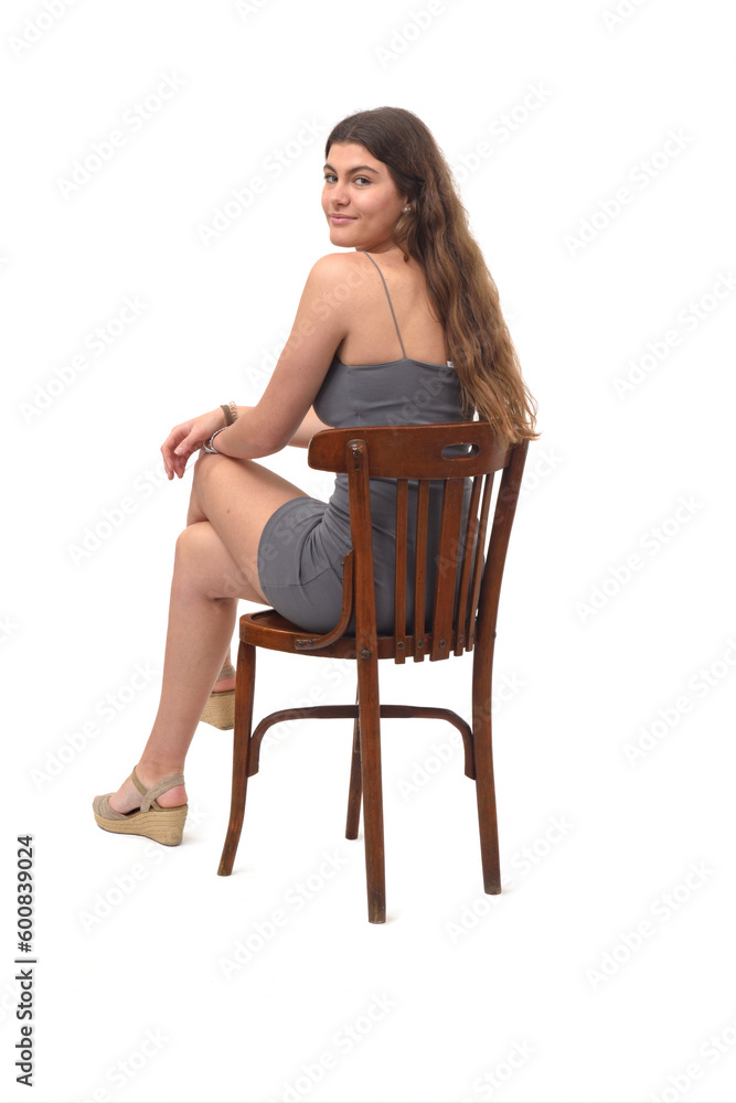 young girl sitting on chair turned and looking at camera on white background young girl sitting on chair turned and looking at camera on white background