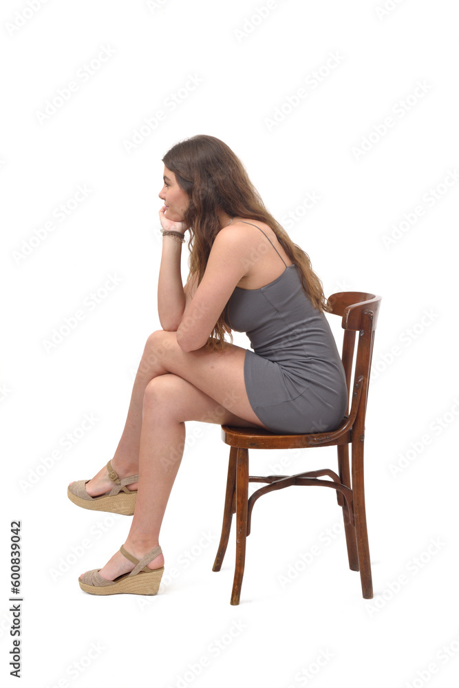 side view of young girl sitting on chair cross legged and hand on chin on white background side view of young girl sitting on chair cross legged and hand on chin on white background