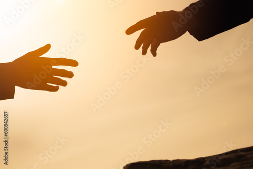 silhouette of hands on the mountain close-up, a man gives a hand to a girl on a mountain, the concept of mutual assistance, motivation for success, there is a place for an inscription. Helping hand