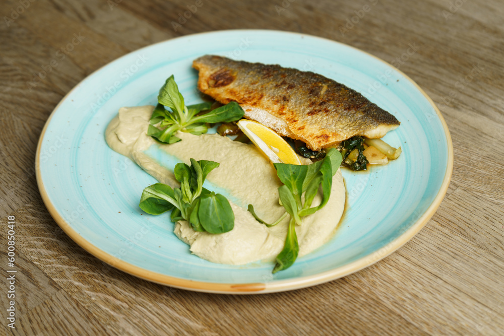 Fried branzino fish fillet with artichoke cream and fried pak choi with