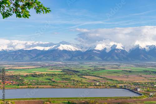 Photography of the beautiful Transylvanian landscape with countryside crops, lake and Fagaras mountains in the background. Photography was taken from a higher ground using a wide angle lens.