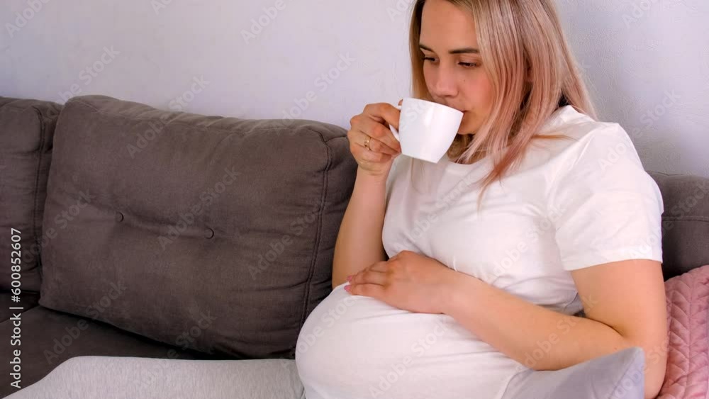 Pregnant woman drinking coffee at home. Selective focus.