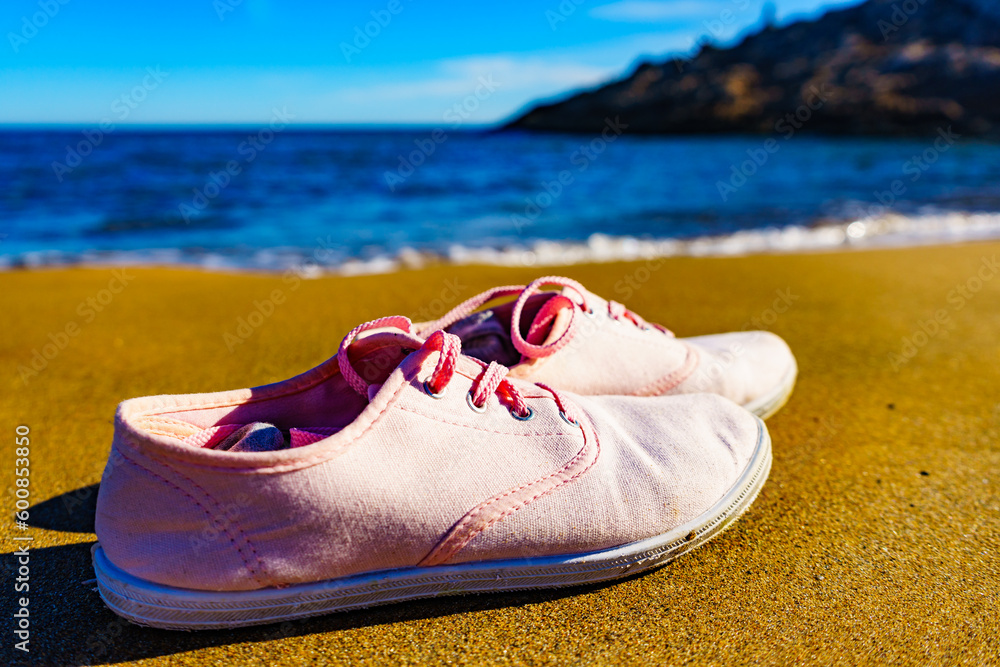 Naklejka premium Female sneakers on sand beach