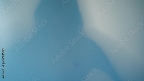 Shadow Blur of a horror man behind frosted glass. Blurred hand, body shape abstraction and one palm. Reflection of the silhouette through the light.