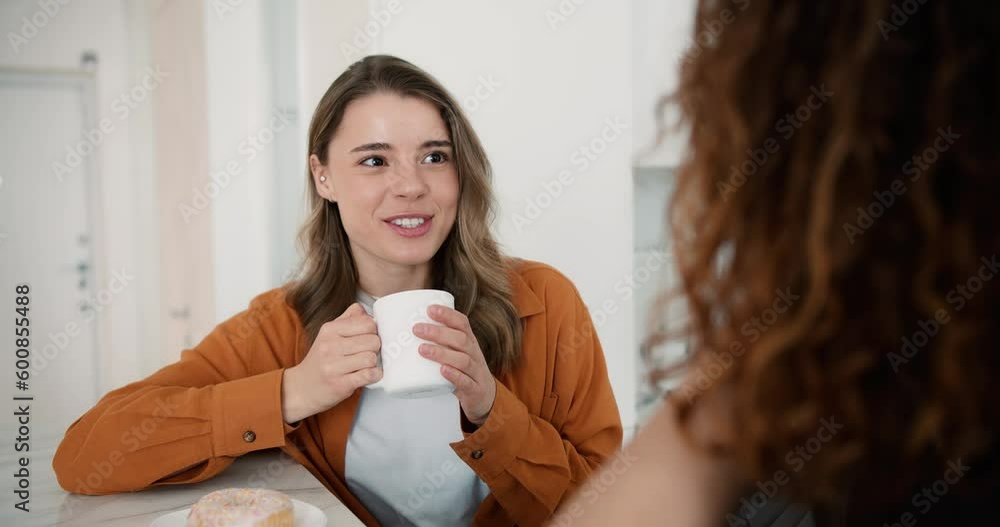 Woman talks with unrecognizable man sitting at the table at the kitchen, eating dessert Woman talks with unrecognizable man sitting at the table at the kitchen, eating dessert