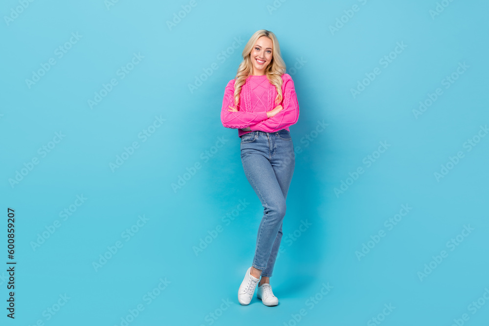 Portrait of satisfied pleasant woman curly hairstyle wear knit pullover denim pants standing arms folded isolated on blue color background Portrait of satisfied pleasant woman curly hairstyle wear knit pullover denim pants standing arms folded isolated on blue color background