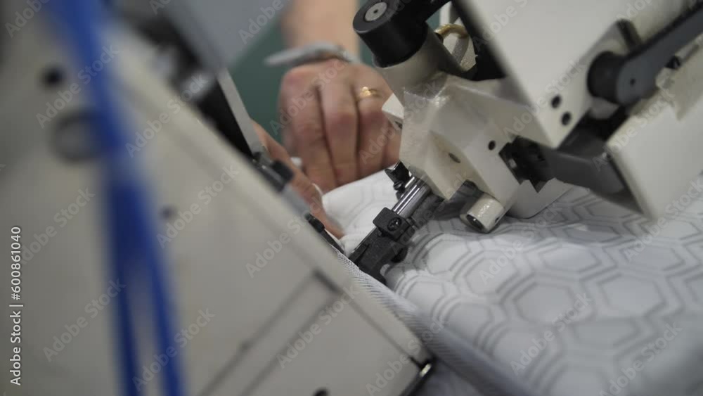 The process of creating from fabric in an electric sewing machine and sews the stitch along the edge into the bending. Female hands sewing on professional sewing machine. The process of creating from fabric in an electric sewing machine and sews the stitch along the edge into the bending. Female hands sewing on professional sewing machine.