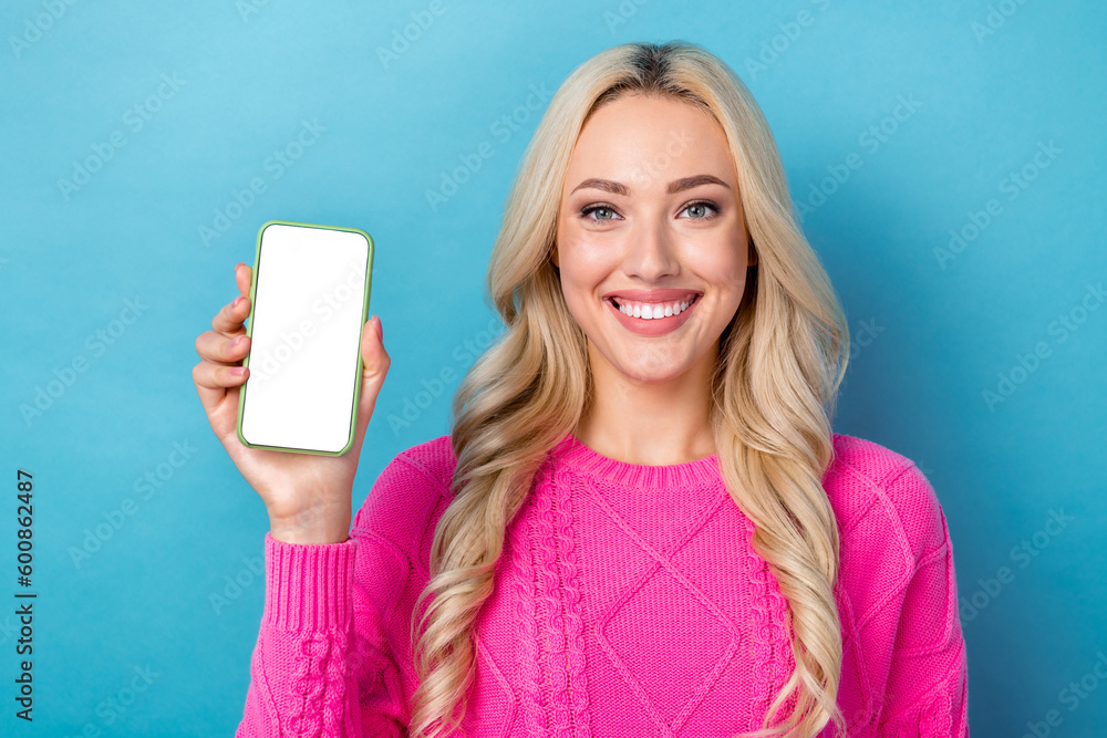 Photo of adorable cheerful lady wear pink sweater showing modern device empty space isolated blue color background Photo of adorable cheerful lady wear pink sweater showing modern device empty space isolated blue color background