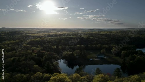 Sunset over wooded area with lakes and a house
