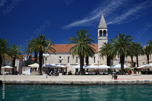 view of palm tree covered promenade of Trogir with church from the sea