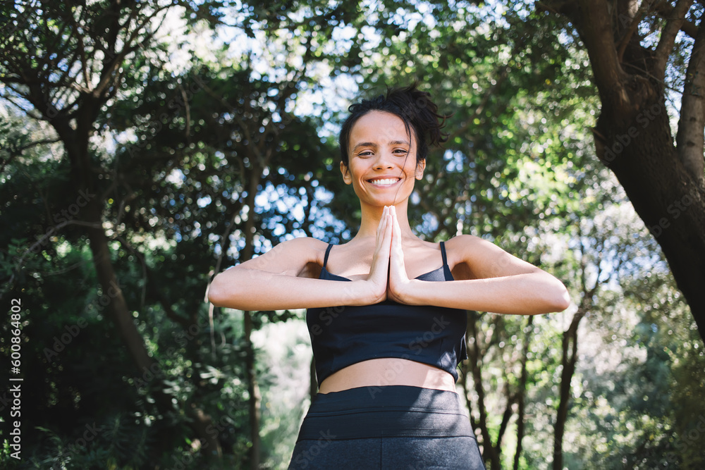 Cheerful ethnic woman practicing yoga against trees Cheerful ethnic woman practicing yoga against trees