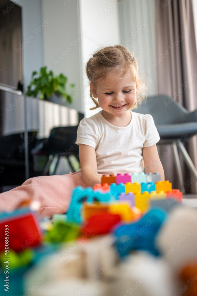 Little girl play with constructor toy on floor in home, educational game, spending leisure activities time concept Little girl play with constructor toy on floor in home, educational game, spending leisure activities time concept