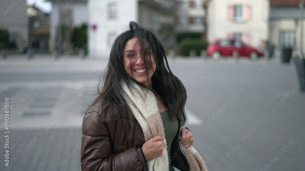 One happy carefree young woman running outside in urban street turning head toward camera in slow motion and smiling One happy carefree young woman running outside in urban street turning head toward camera in slow motion and smiling
