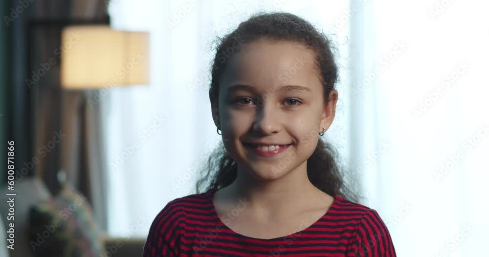 Portrait of a beautiful little girl, a smiling child in a red dress, looking at the camera, sits on the sofa at home, a cute child with a beautiful face sits on the sofa. Happy childhood concept. 4K Portrait of a beautiful little girl, a smiling child in a red dress, looking at the camera, sits on the sofa at home, a cute child with a beautiful face sits on the sofa. Happy childhood concept. 4K
