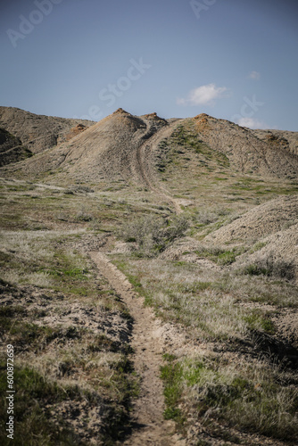 Trail running through clay mounds of dirt in green grassy hills in western Colorado near Fruita in spring photo
