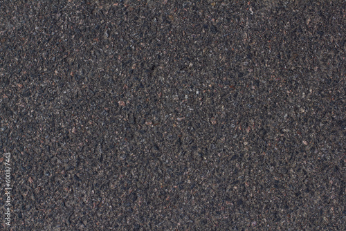 Background of an asphalt road close-up with small stones. Smooth asphalt road for cars. Uneven grainy texture of an asphalt road close-up.