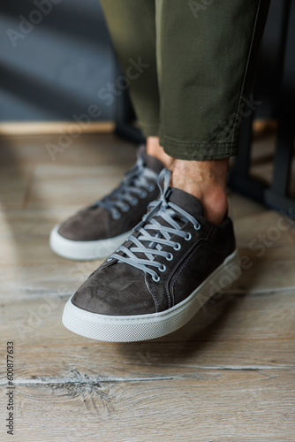 Close-up of male legs in pants and gray casual sneakers. Men's leather shoes. Collection of men's stylish summer shoes