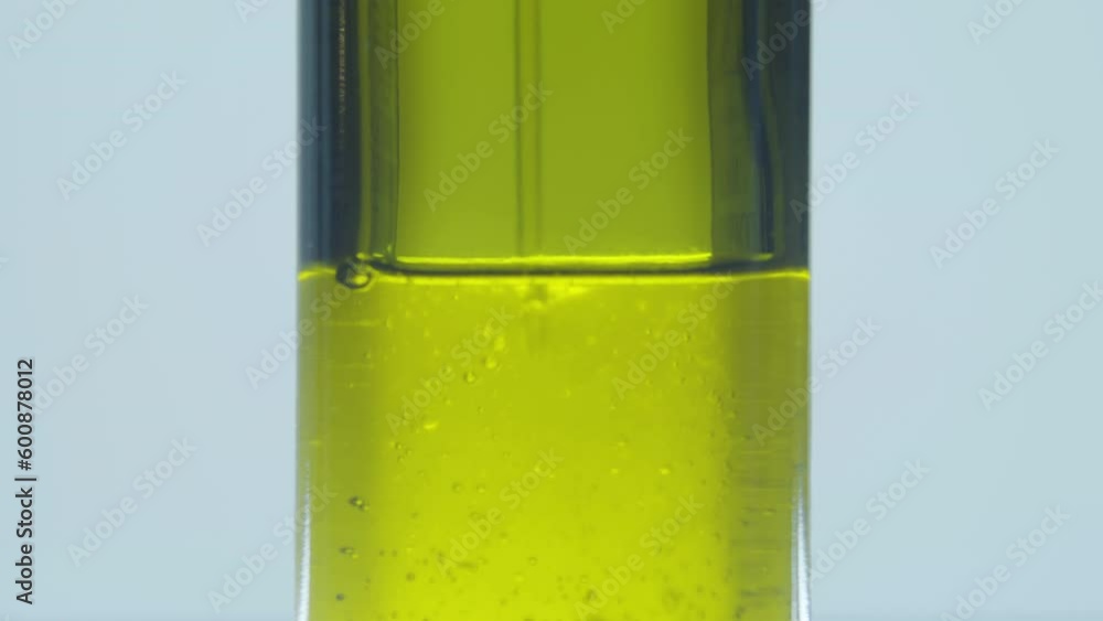 Motor oil in a glass tube. Process of cleaning and adding additives to engine oil. Energy and fuel. Obtaining Natural Oil by Cold Pressing. Air Bubbles. Macro photography. Cosmetology. Motor oil in a glass tube. Process of cleaning and adding additives to engine oil. Energy and fuel. Obtaining Natural Oil by Cold Pressing. Air Bubbles. Macro photography. Cosmetology.