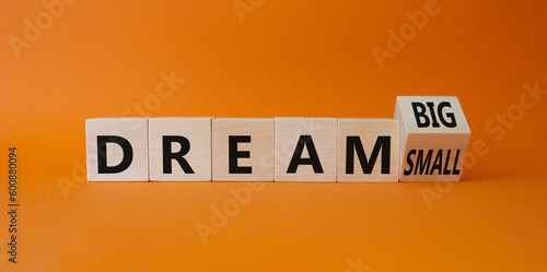 Dream Big vs Small symbol. Wooden cubes with words Dream Small and Dream Big. Beautiful orange background. Business and Dream concept. Copy space