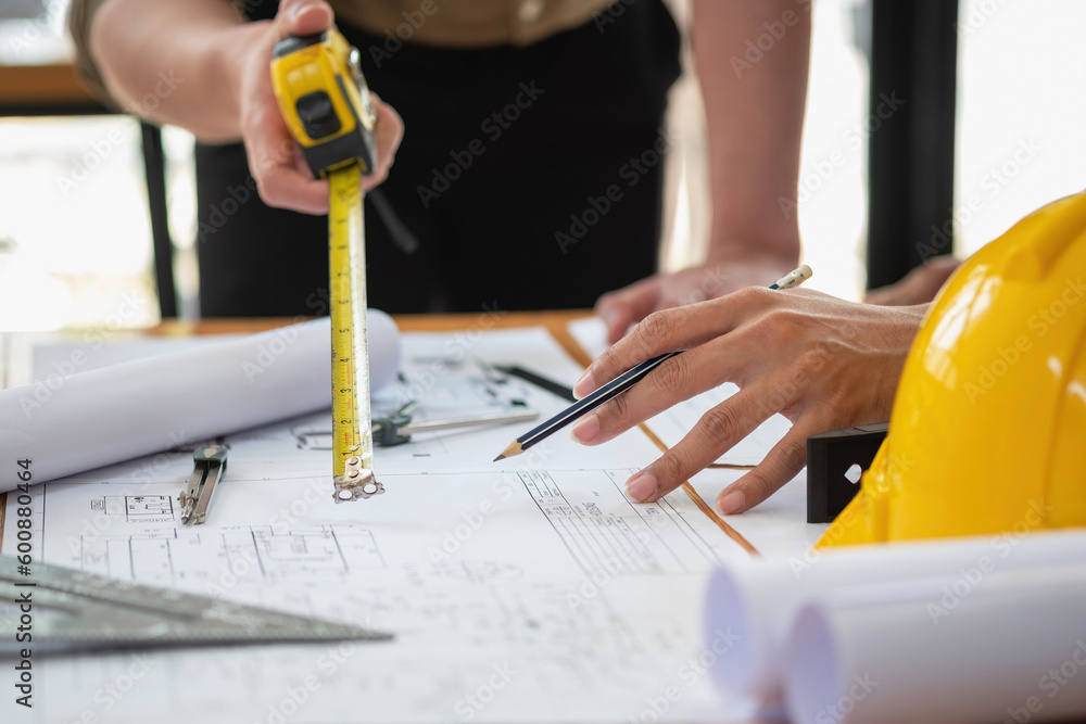 Asian engineers brainstorm and measure to document cost estimates and write floor plans for architectural and engineering designs for houses and buildings. Asian engineers brainstorm and measure to document cost estimates and write floor plans for architectural and engineering designs for houses and buildings.