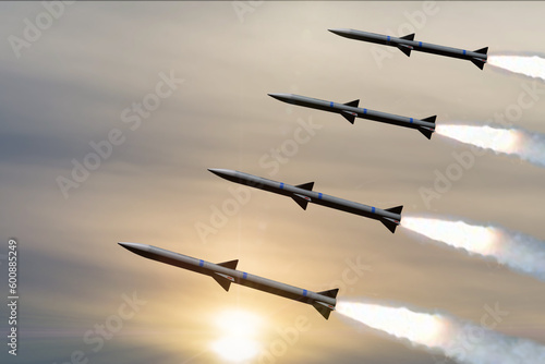 Obraz na plátně Military missiles fly against the background of the sunset sky, leaving behind white smoke, a volley of missiles