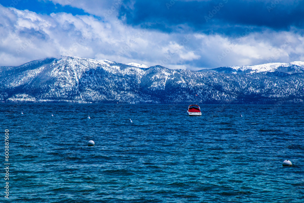 View of Lake Tahoe from the North Side with a single boat docked in the water, looking over to the Northeast side of Incline Village