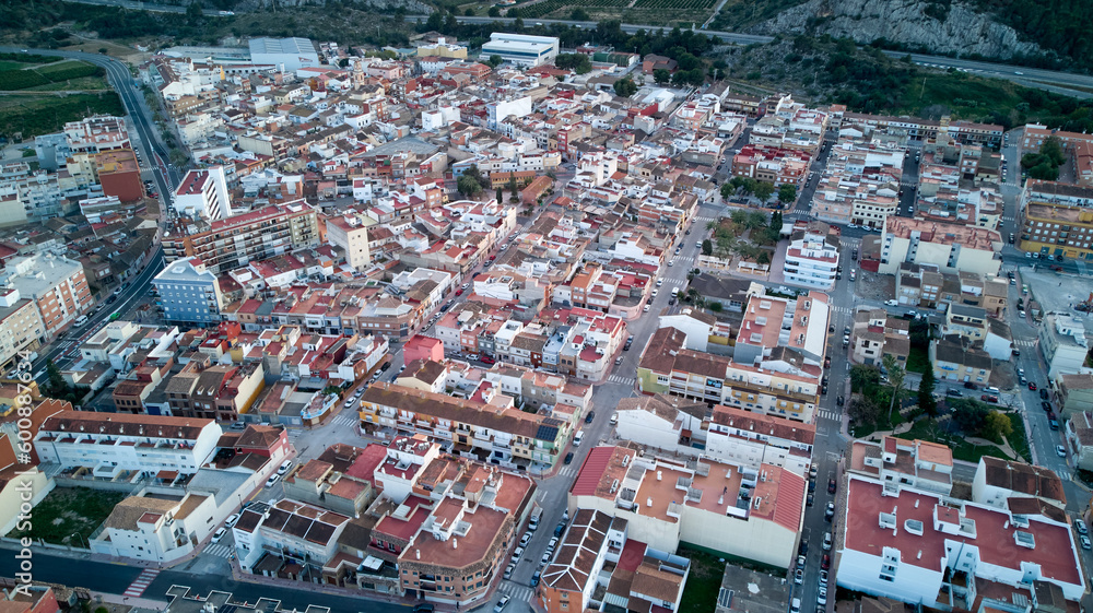Aerial view of a lively Spanish city with red-roofed buildings, narrow streets, mountains, and buildings of varying height and style.