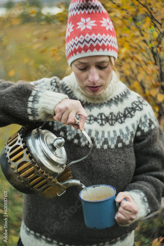 Woman pouring a tea from kettle outdoors in autumn nzture photo