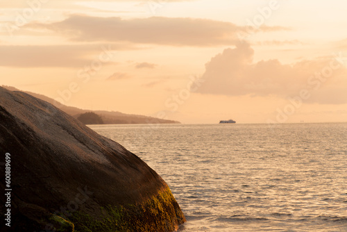 Golden sunset between rocks at Ilhabela beach. Paradisiacal and tropical Brazilian beach. Rocks concept. Golden sunset concept.