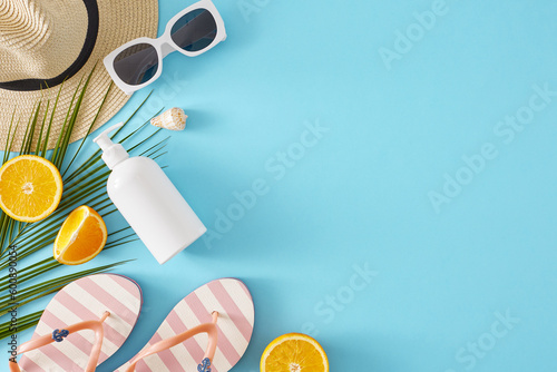 Seaside vacation concept. Top view flat lay of stylish sunhat  sunscreen bottle  flip-flops  sunglasses  orange slices and palm leaf on light blue background with space for text or advert