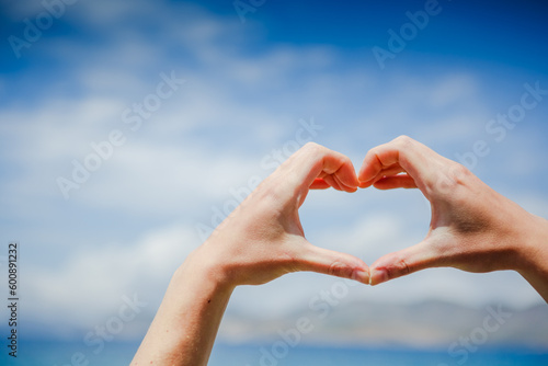 Girl hand in heart form love with ocean sunset background © olyphotostories