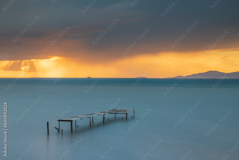 Obraz premium Wooden pier built into the sea and helping fishing, sunset colors and light
