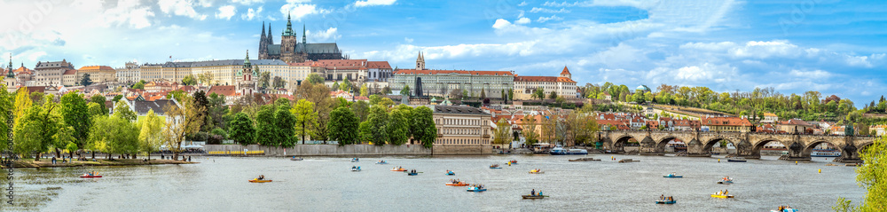 Obraz premium A panoramic view of Prague, the capital of the Czech Republic. View of Prague Castle and Charles Bridge. Summer time, people swim on catamarans. banner