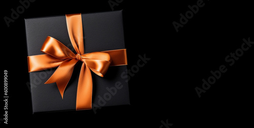 black Gift box with Orange bow isolated on black background