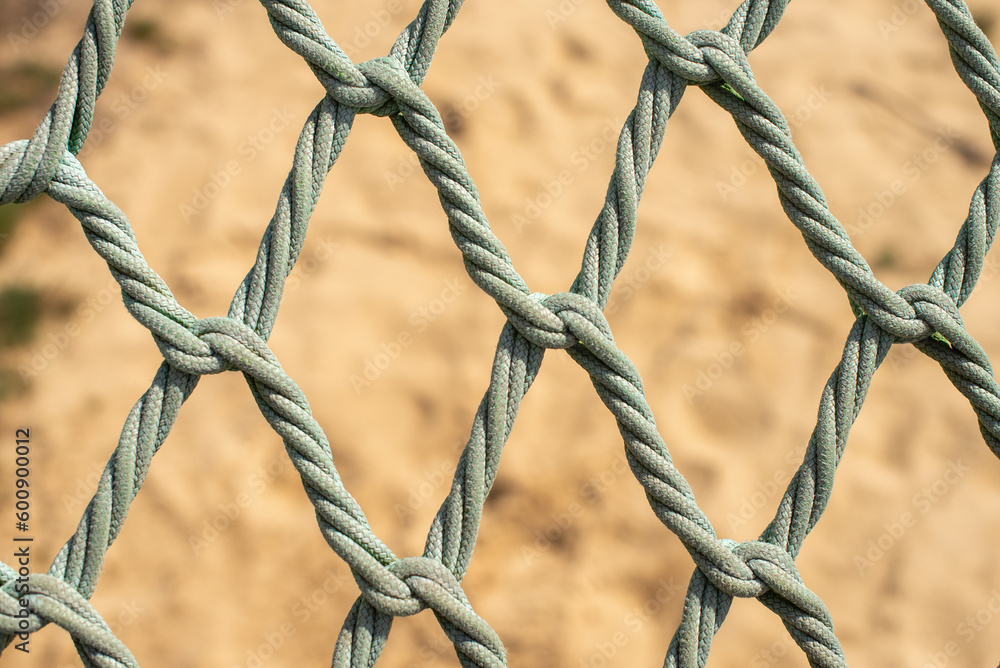 Playground safety net over a sandy background. Knotless Rope. Braided rope