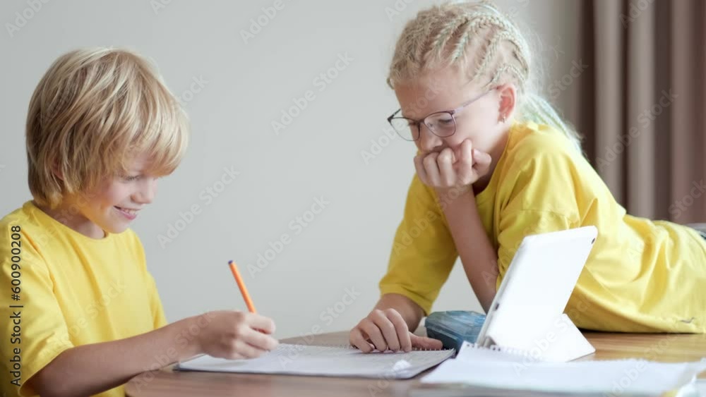 Sister helps little brother do school homework at home, Distance learning online education, boy and girl studying at home with digital tablet. Sister helps little brother do school homework at home, Distance learning online education, boy and girl studying at home with digital tablet.