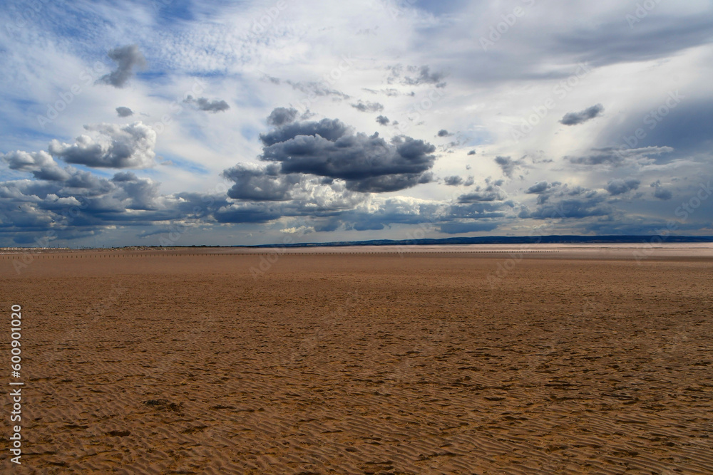 Brooding clouds in a blue sky over a flat empty beach