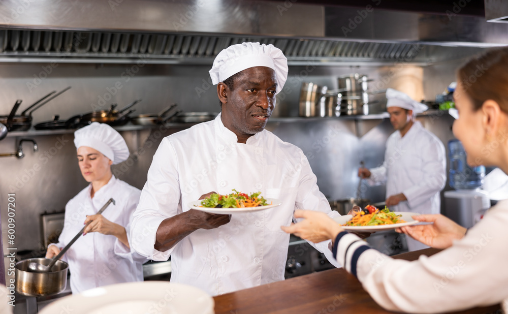 African american chef serving ready meals to visitors of restaurant