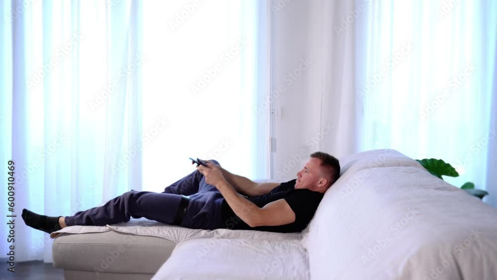 Joyful guy jumps over sofa takes TV remote controllers Joyful guy jumps over sofa takes TV remote controllers