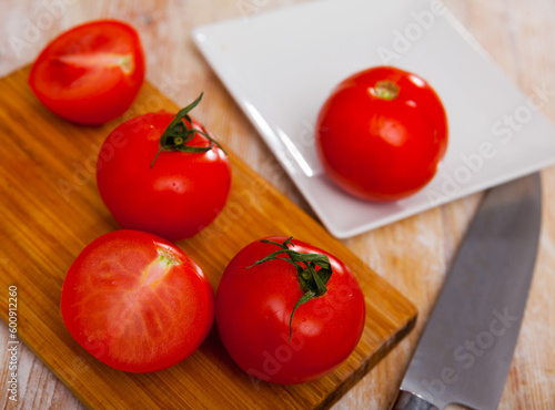 Fresh juicy organic tomatoes on wooden kitchen table