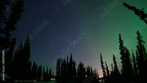 Stunning northern lights display seen in northern Canada from Yukon Territory on a frozen lake at night time with purple, green bands of Aurora Borealis showing across the arctic sky.  photo