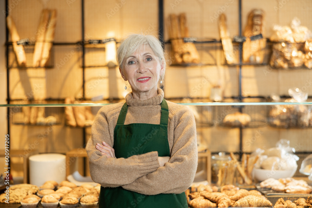 Mature female baker confidently welcoming customers into her bakery