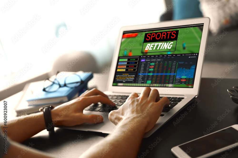 Man betting on sports using laptop at table, closeup. Bookmaker website on screen Man betting on sports using laptop at table, closeup. Bookmaker website on screen
